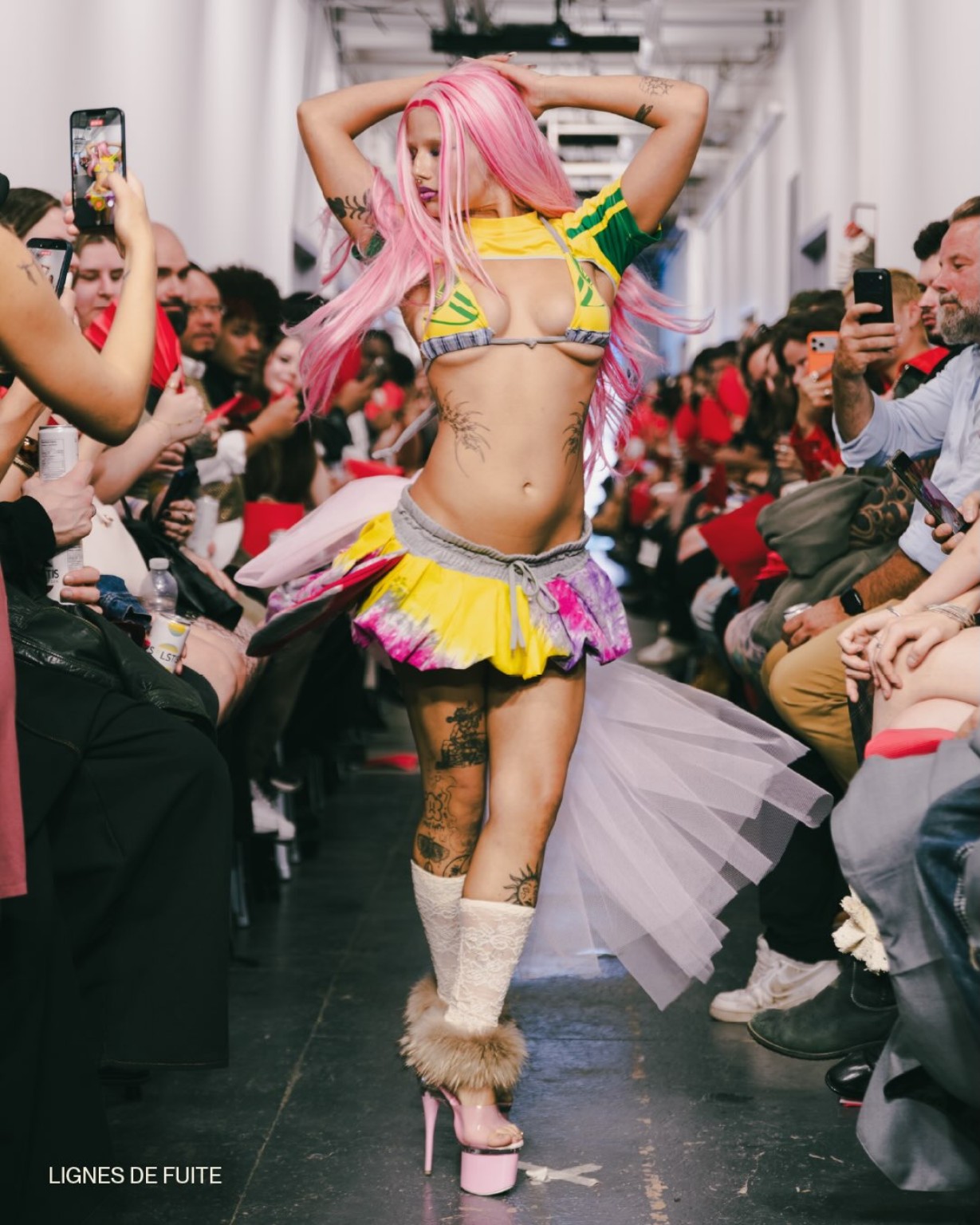 A pink-haired model in a yellow and green runway look at ON SHOW during Montréal Fashion Week.