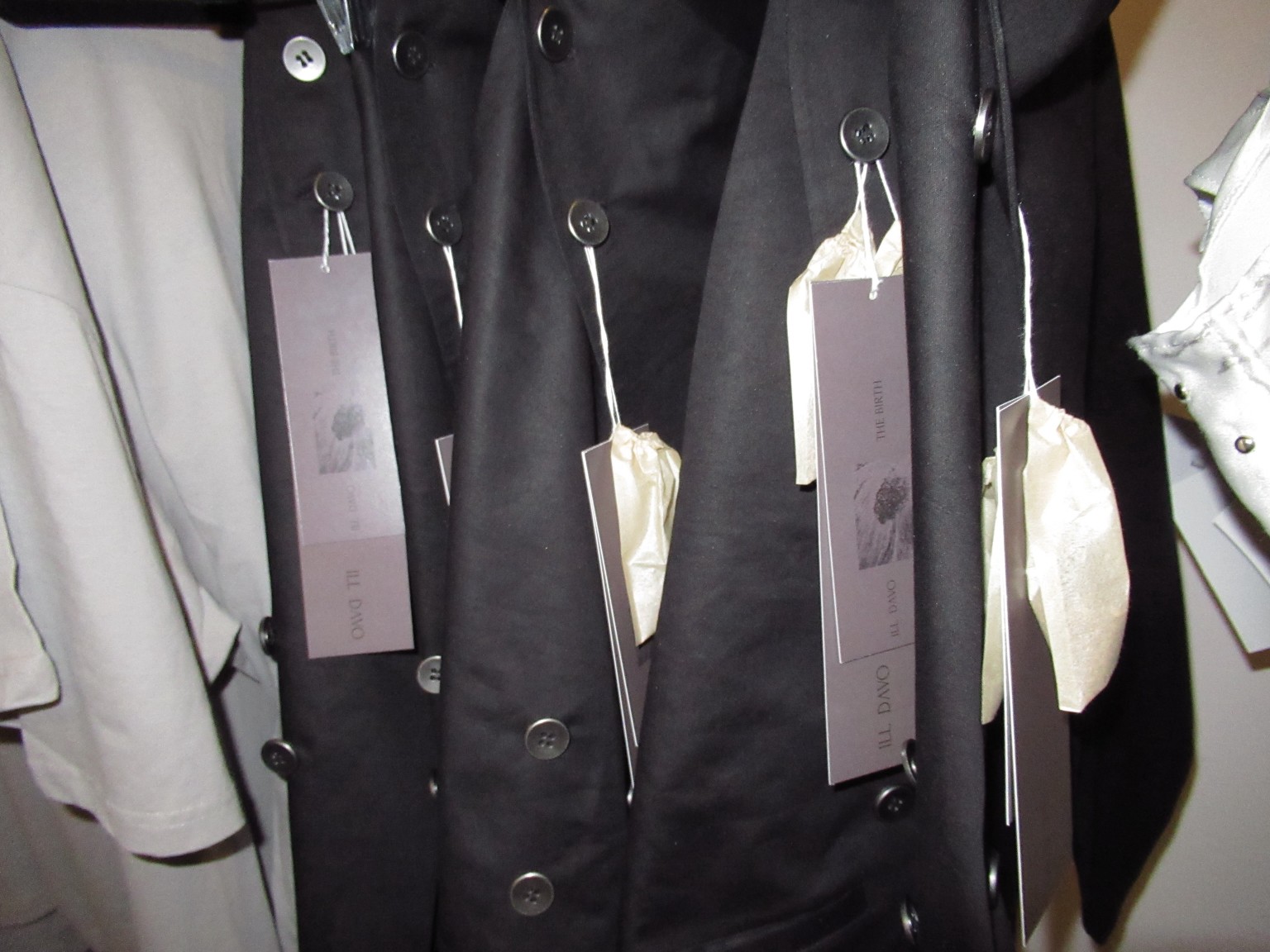 Black ILL DAVO garments with collection tags, presented in the LDF multibrand showroom.