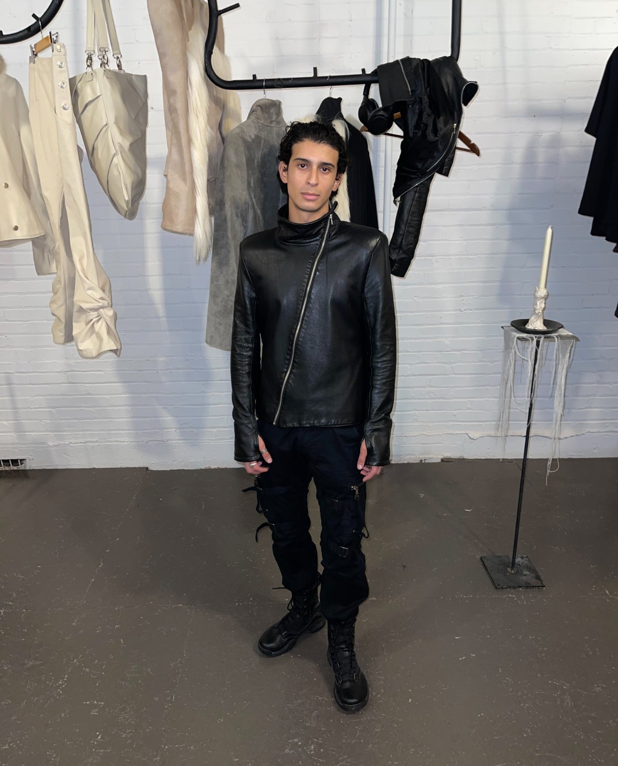 Visitor wearing a black leather jacket in front of designer garments at the LDF showroom during Montréal Fashion Week 2026.