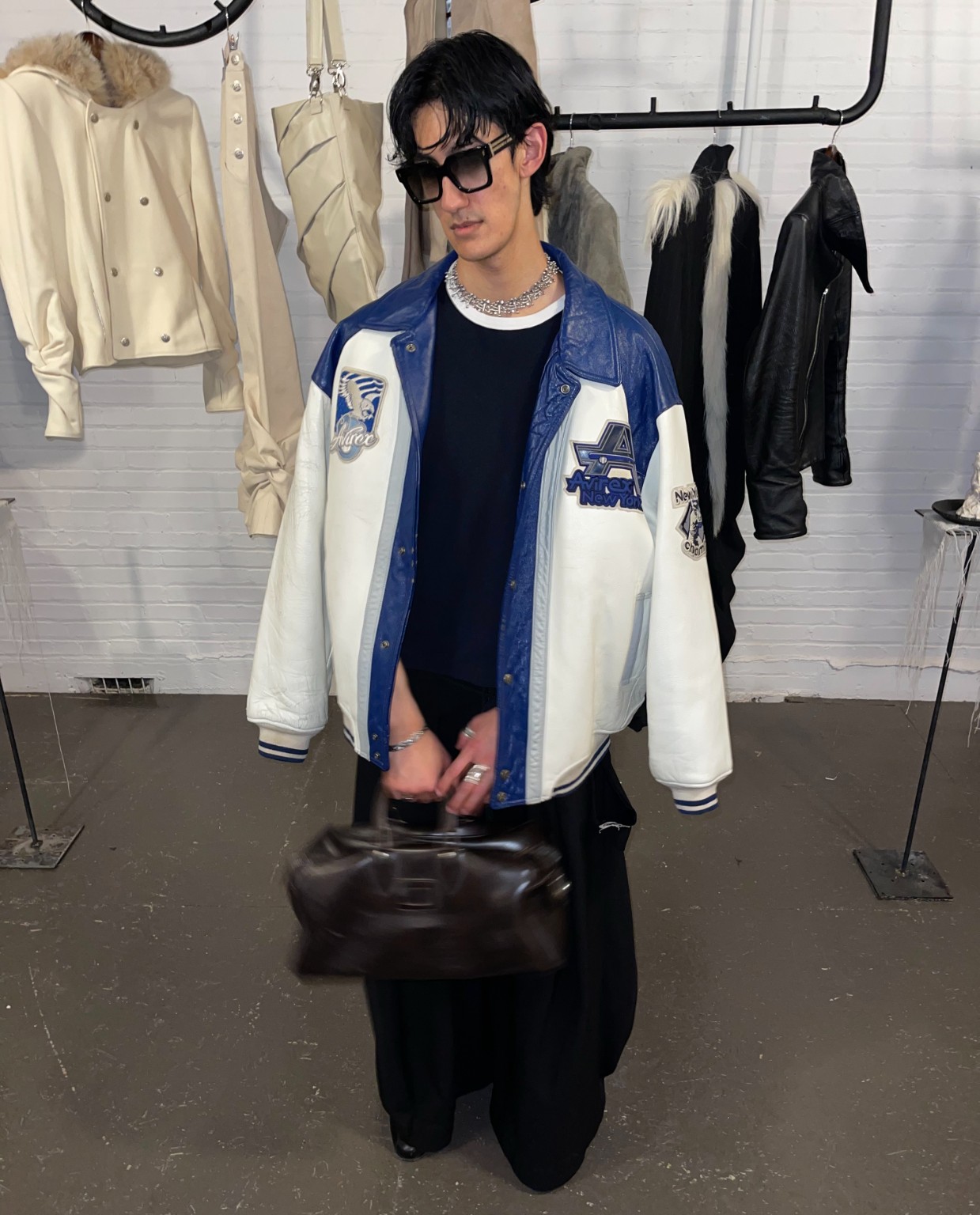 Visitor wearing a blue and white leather varsity jacket at the LDF showroom during Montréal Fashion Week 2026.