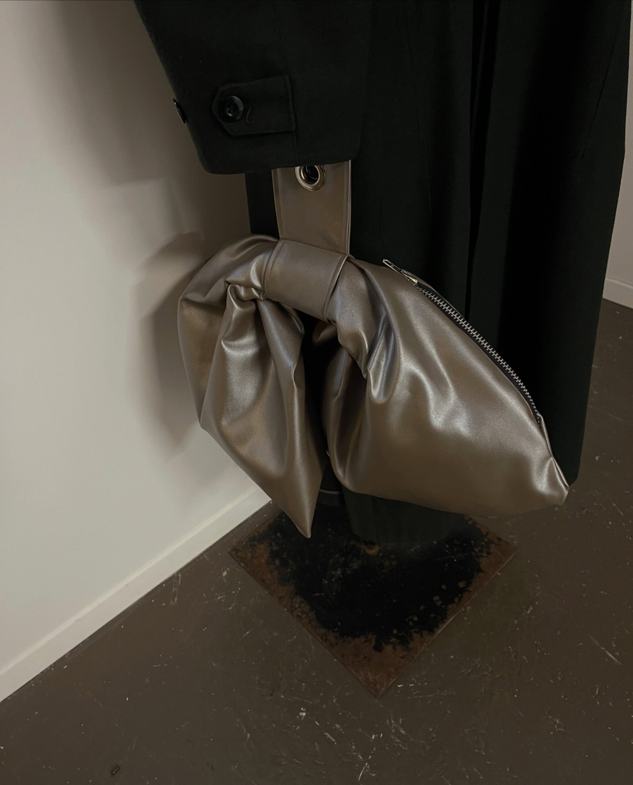 Metallic sculptural bag displayed with garments inside the LDF showroom during Montréal Fashion Week 2026.